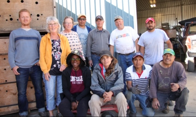Eleven Poplar Bluff Organics farm team members standing and sitting outside the production house in summer